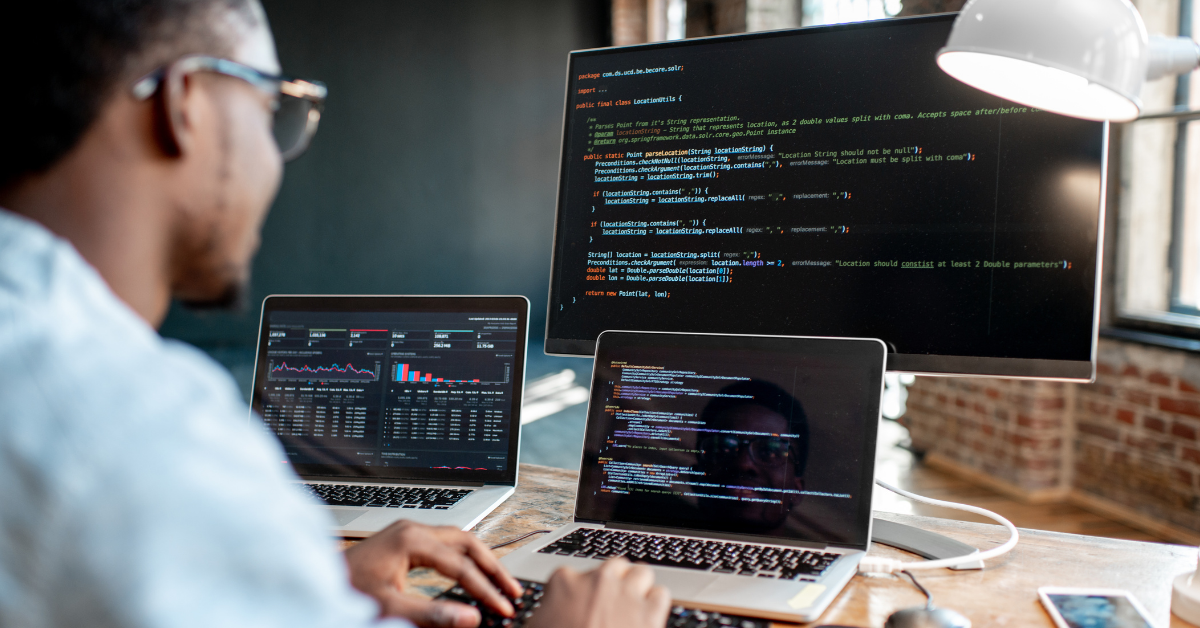 Developer looking at code on multiple screens